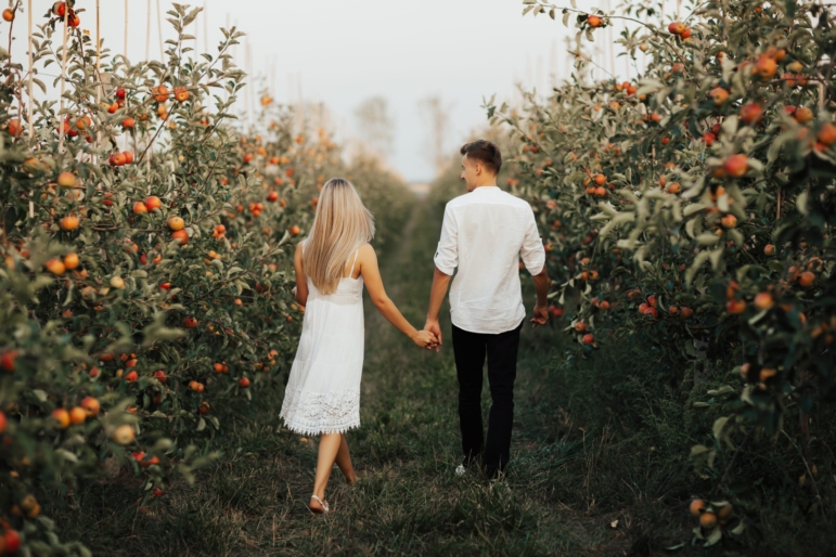 A couple walking through a foggy apple orchard in their own secret world